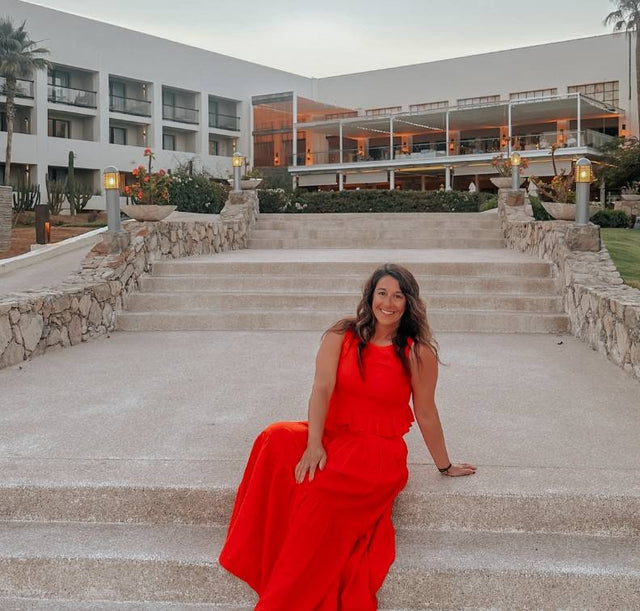 Cariloha ambassador Aileen Bayliss sitting on the stairs of a beach resort on the ambassador rewards trip