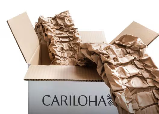 A white box with the brand name CARILOHA printed on the front, filled with crumpled brown packing paper against a white background.