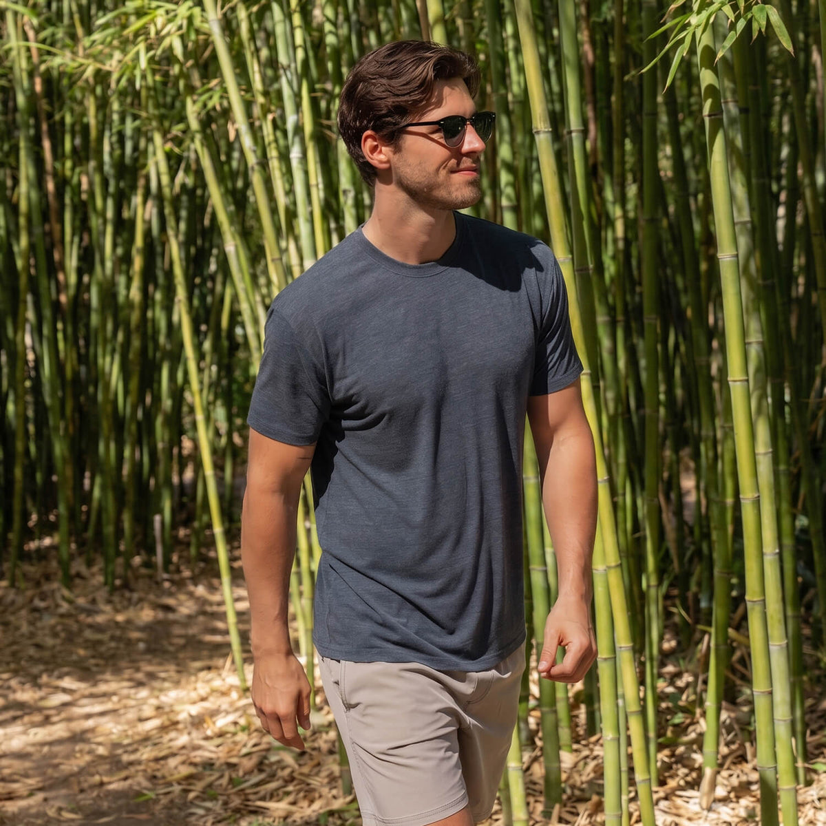 a man walking through a bamboo forest wearing a gray cariloha t-shirt