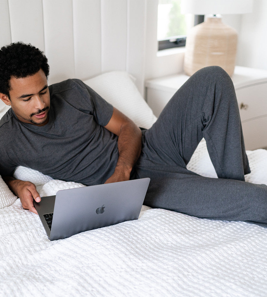 model lying in bed wearing charcoal heather pants