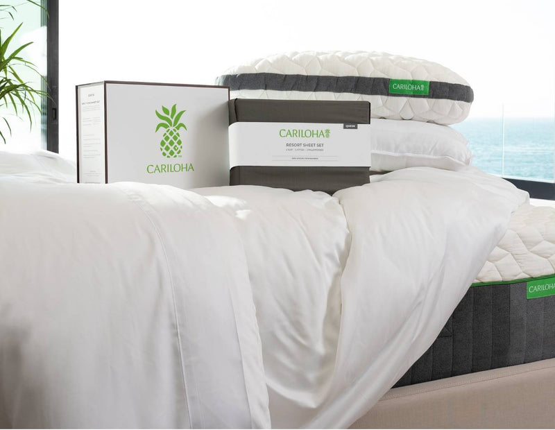 Cariloha-branded pillow, boxed Resort Sheet Set, and mattress staged on a bed overlooking the ocean